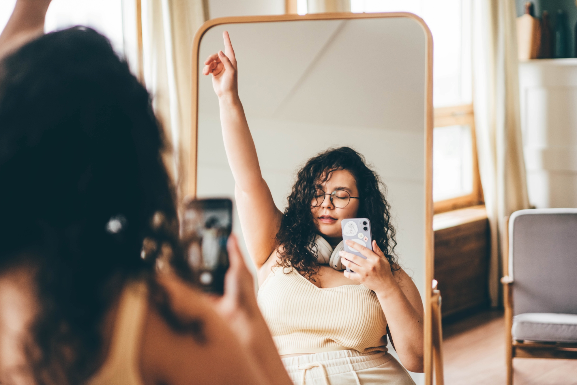 Woman raising arm in celebration in front of a mirror