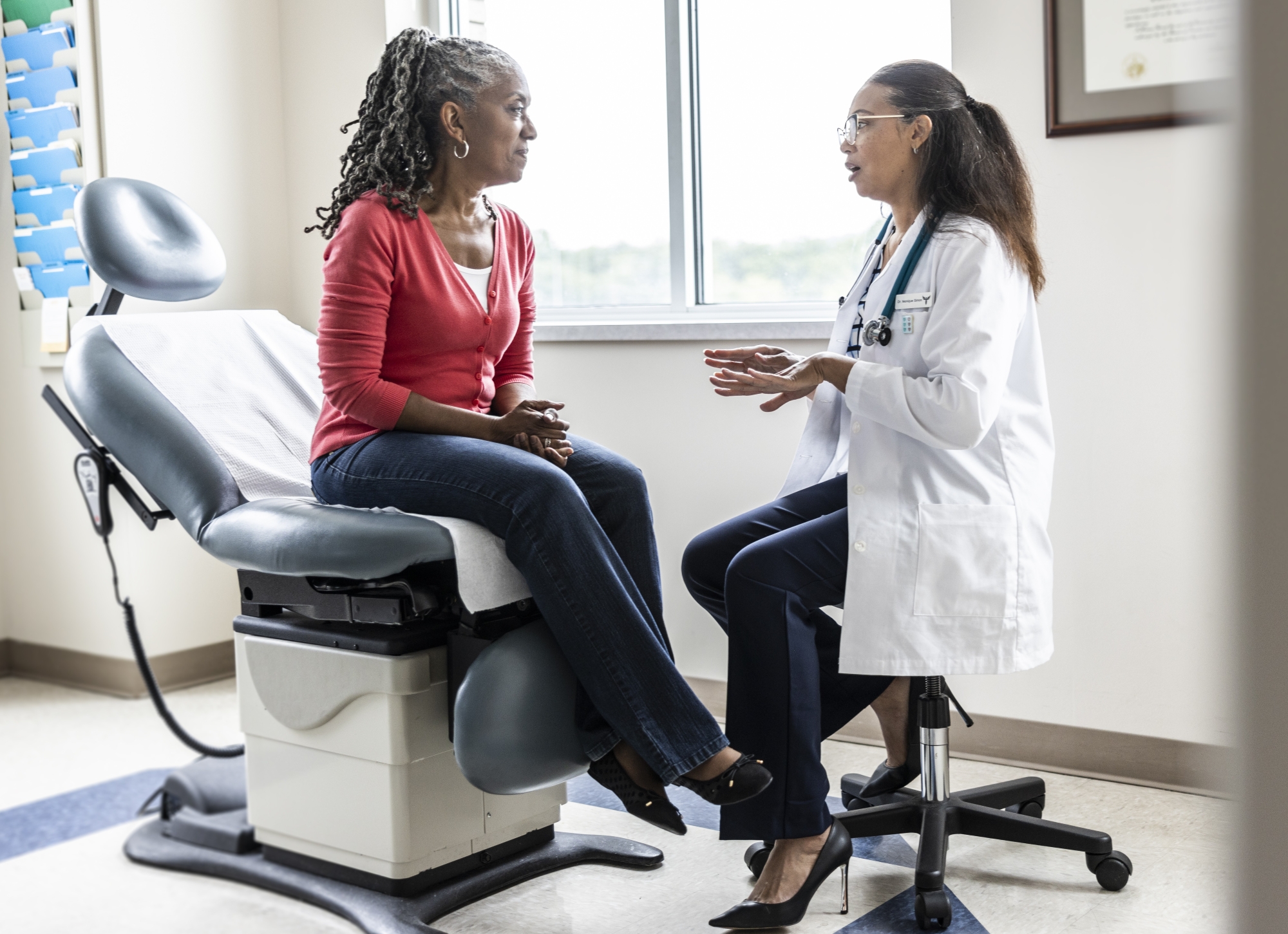A female patient is talking with female doctor in an exam room.