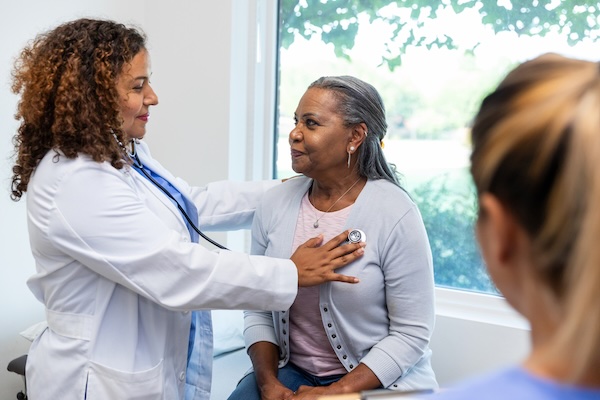 Healthcare provider listens to a female patient's heart with a stethoscope