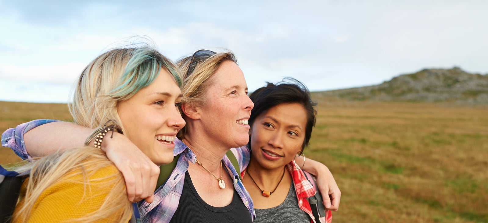 Happy hiking female friends huddle together on a rocky moorland