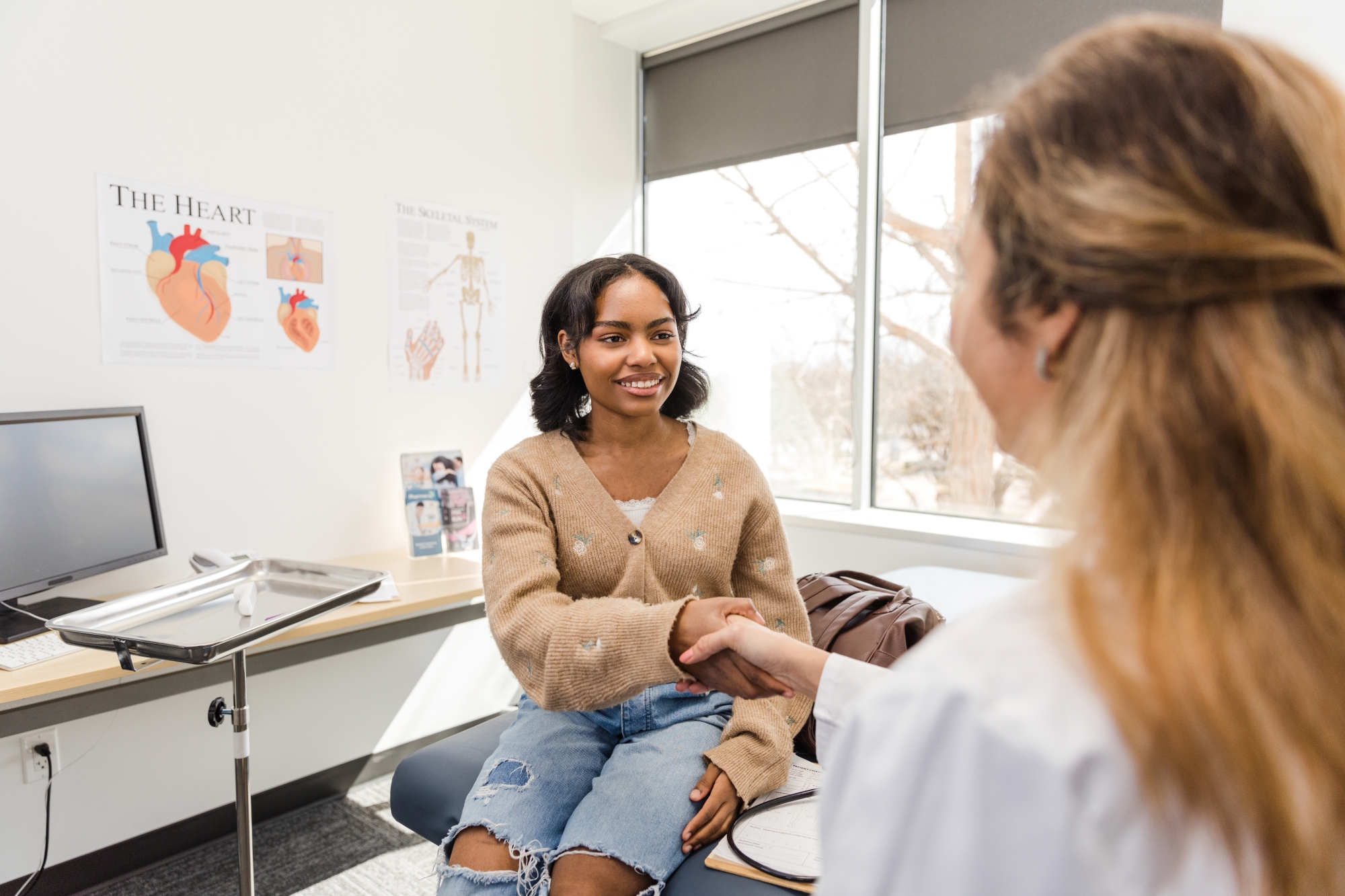 Young adult patient shakes hand as she meets with new physician